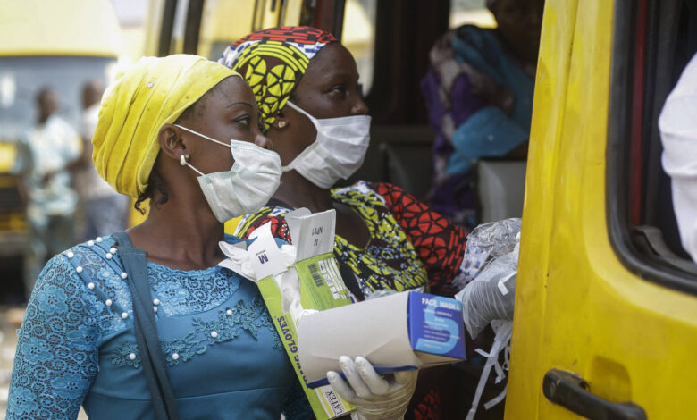 Women sell face masks and gloves, to prevent the spread of the new coronavirus, to passengers at a public minibus station in Lagos, Nigeria Friday, March 27, 2020. The new coronavirus causes mild or moderate symptoms for most people, but for some, especially older adults and people with existing health problems, it can cause more severe illness or death. (AP Photo/Sunday Alamba)