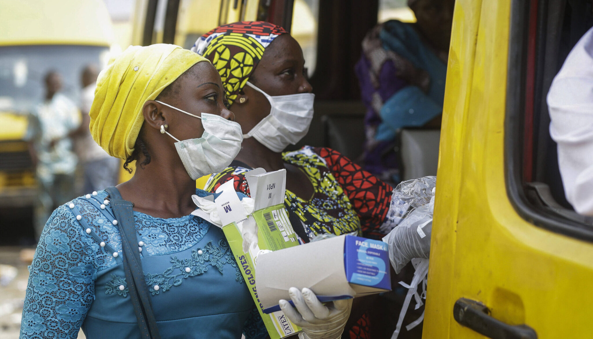 Women sell face masks and gloves, to prevent the spread of the new coronavirus, to passengers at a public minibus station in Lagos, Nigeria Friday, March 27, 2020. The new coronavirus causes mild or moderate symptoms for most people, but for some, especially older adults and people with existing health problems, it can cause more severe illness or death. (AP Photo/Sunday Alamba)
