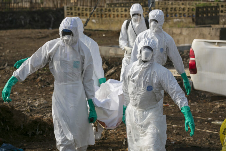 Health workers carry the body of a suspected Ebola victim for burial at a cemetery in Freetown